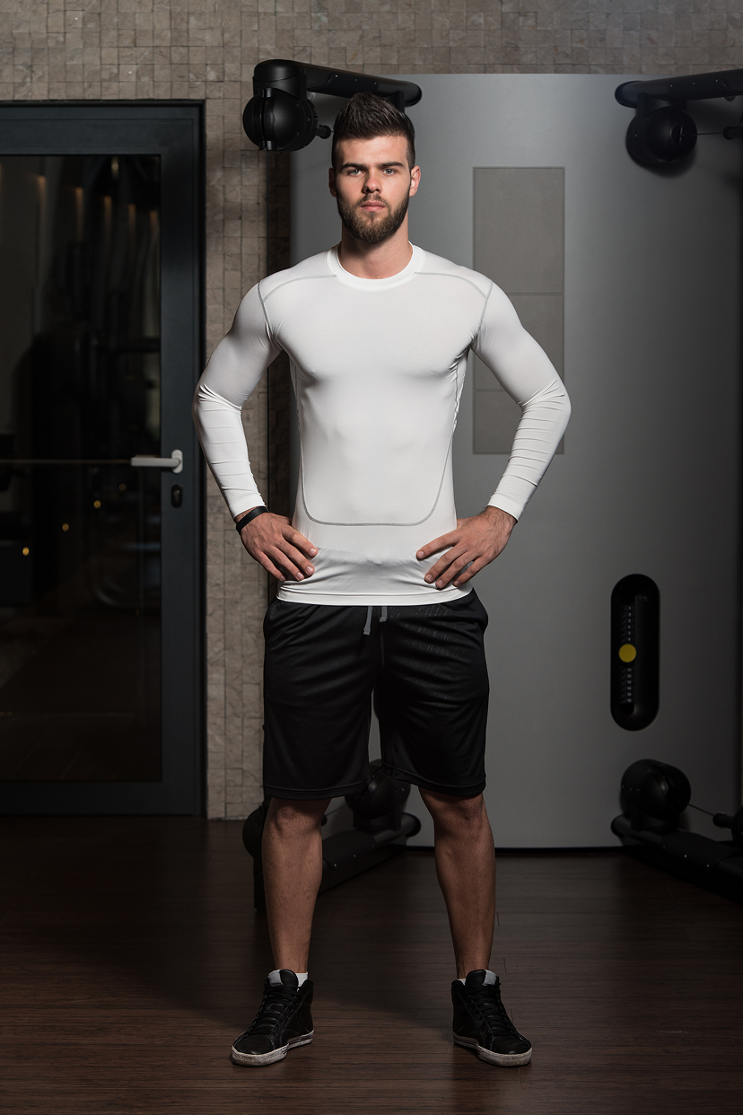 Man in white long-sleeve shirt and black shorts in gym
